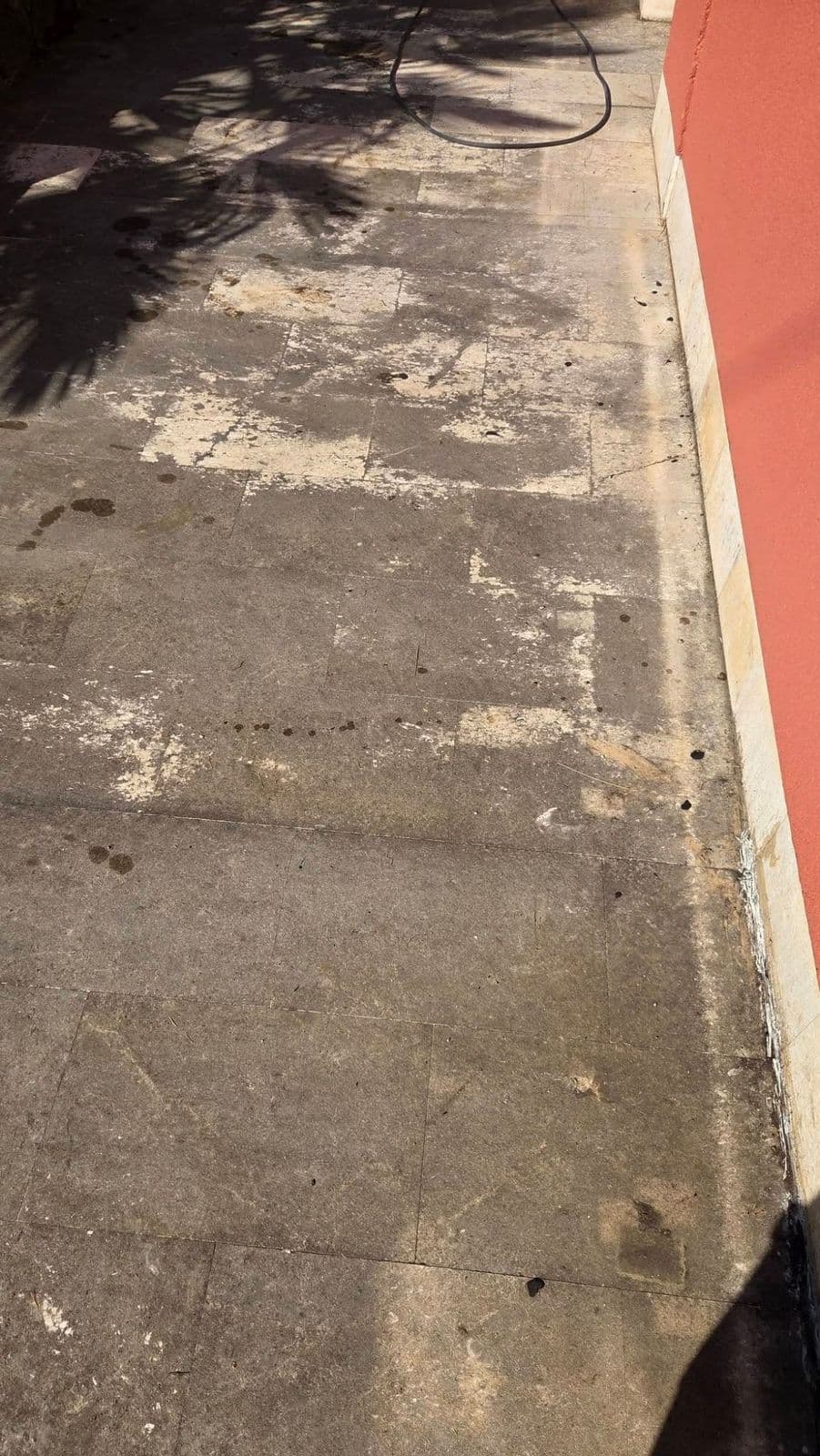 Kamena staza uz crvenu fasadu kuće, tamna s bijelim mrljama prije čišćenja